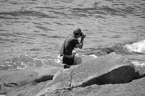 photographer among stones at the water's edge