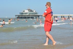 lifeguard in red uniform stands on the background of Belgium Pier