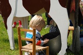 Child looking for milk from a cardboard cow's milk yield