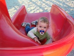 baby with dummy lies on the hill