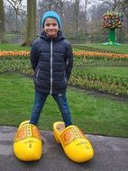 child Boy in giant Wooden Shoes posing in park, netherlands
