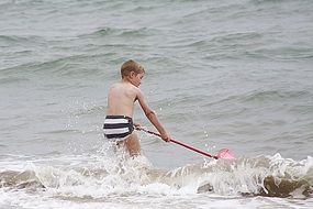 caucasian child boy playnig in sea waves