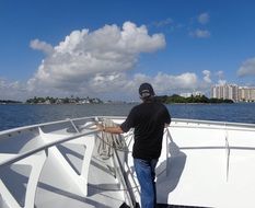 Man on yacht in sea looks at city, usa, florida, miami