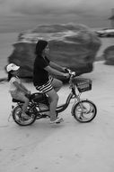 black and white photo mother and child ride a bike along the beach in Vietnam
