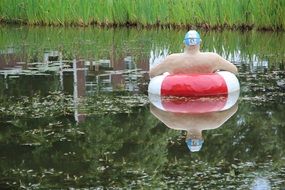 man on a donut at the pond as a sculpture