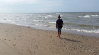 a boy walks along the seashore in Holland