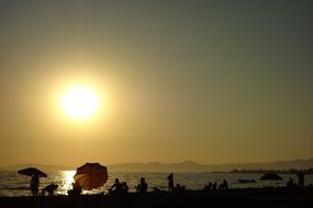 people on the beach near the water during sunset