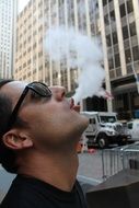 young man in sunglasses blowing Smoke in city, Effect of Perspective