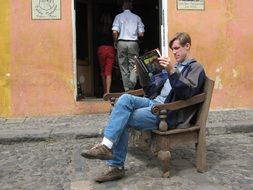 man reading on a wooden chair