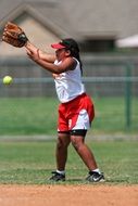 girl in red-white uniform plays football on the field