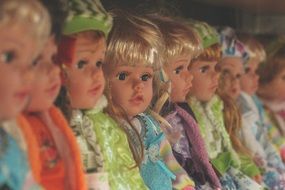 collection of dolls is sitting on one shelf