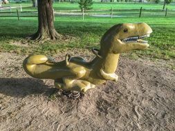 swing in the form of a green dinosaur in a playground