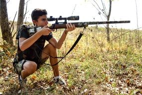 young man with a sniper rifle in the forest