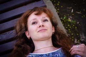 young girl is lying on a bench