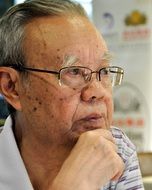 old man with glasses sits and thinks