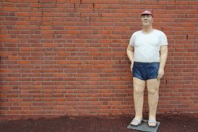 Man Sculpture near a brick wall