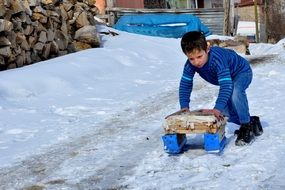 child sledding in the snow in the yard