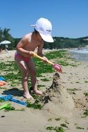 a little girl is building a sand castle on a beach