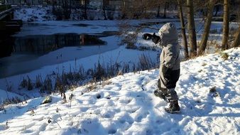 Child near the snowy river in winter