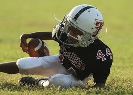 american football player lies on green grass