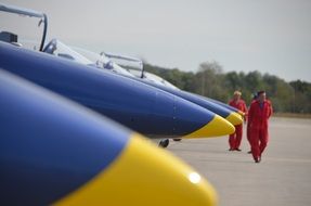 photo of pilots in red suits and yellow-blue fighters