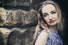 photo of a blonde against a stone wall