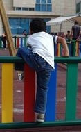 boy climbs over a fence in kindergarten