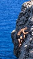 Man climbing on a sea rock