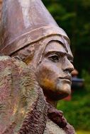 Close-up of the face of a statue in a helmet at blurred background with the plants