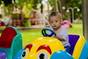 child on a children's car in the park