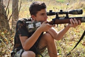 young man with weapon in the forest