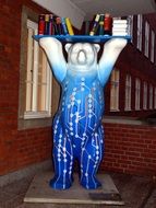 Blue statue of bear with books on it
