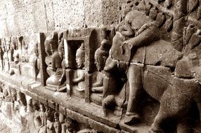 figures of people and animals on the wall of the temple in cambodia
