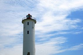 white lighthouse on a background of blue clouds