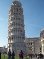 tourists stand against the white leaning tower of Pisa in Italy