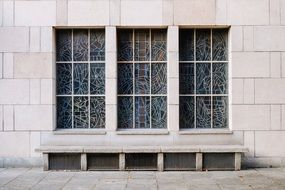 three stained glass Windows above stone Bench