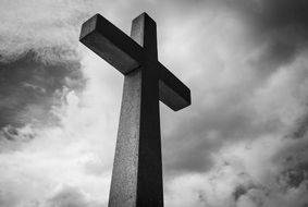 black and white photo of a stone cross against a cloudy sky