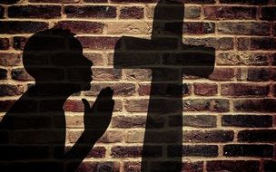 shadows from the cross and prayer on a brick wall