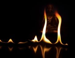 fire near buddha statue at dark background