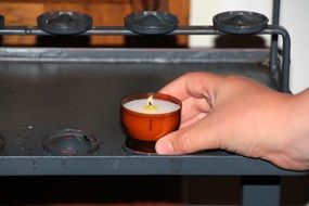 man puts a burning candle in the church