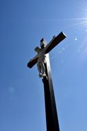 cross with a crucifix on blue sky background under the bright sun