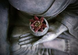 statue of meditating Buddha with flower in hand