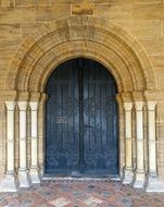 stone arch and wooden doors to the Church