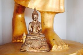 Buddha at the feet of a golden statue in a Bangkok temple