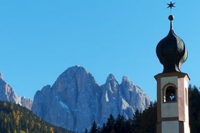 bell tower of Church St. Johann beneath Geislerspitzen range, Dolomites, italy