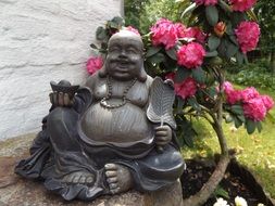 bush of rhododendron and buddha statue
