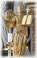 golden angel with a bible near a candle