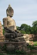 large statue of a buddha among the ruins in Ayutthaya