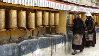 pilgrims near prayer wheels in tibet