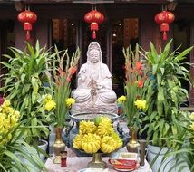 orchids and gladioli in front of a religious statue in Vietnam